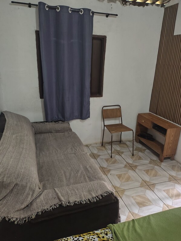Une pièce comprenant un lit, une chaise, une petite table et une fenêtre.