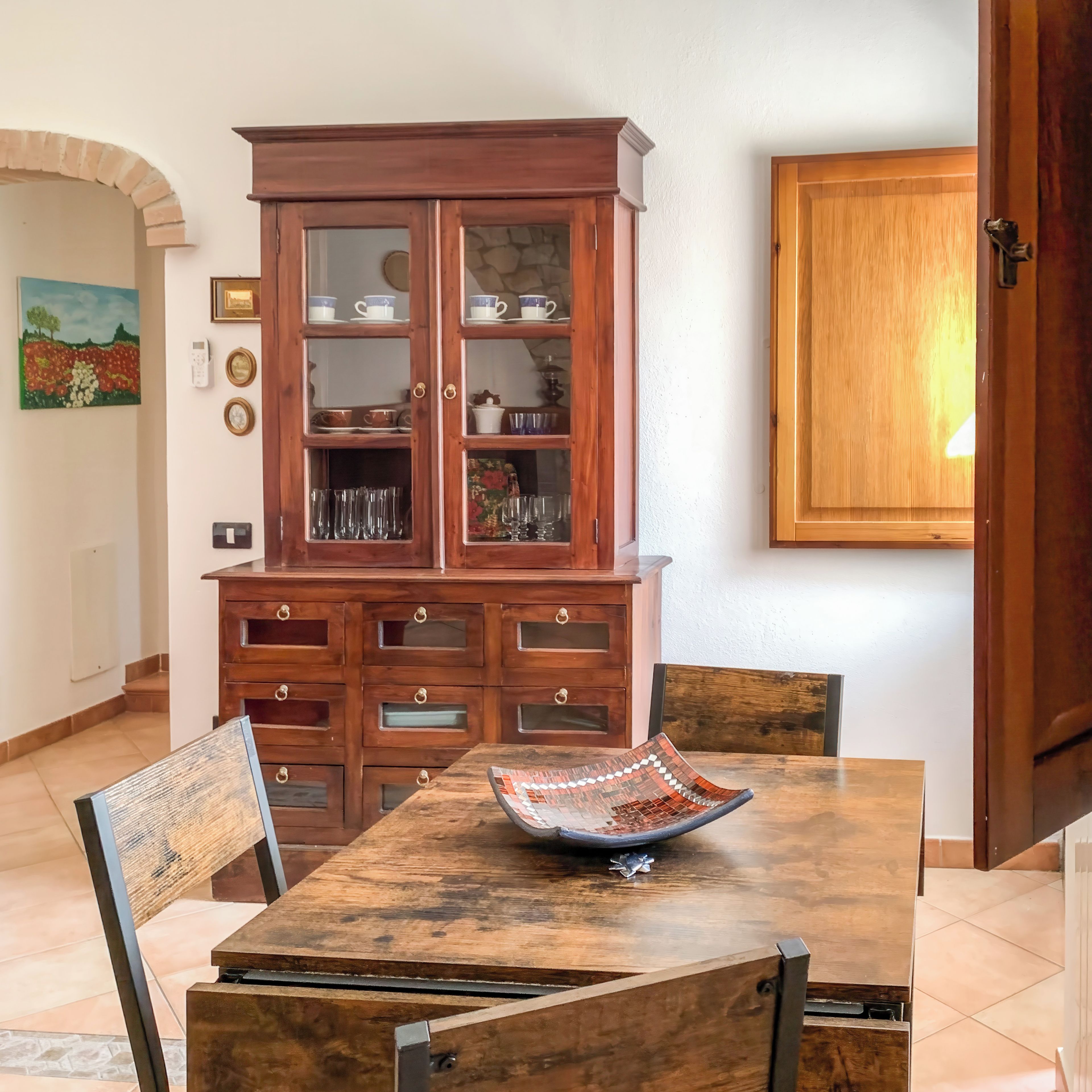 A dining area with a wooden table, chairs, and a cabinet with glass doors.
