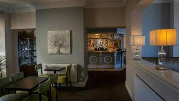 Habitación de hotel con comedor, bar y vistas de la ciudad.