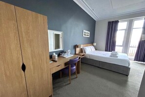 A hotel room with a bed, a desk, a chair, a wardrobe, and a window. - Double room with sea view (Llandudno)
