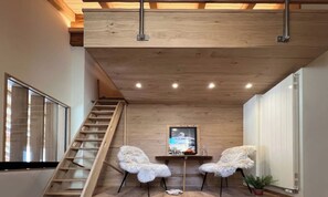 A loft-style room with a wooden ceiling, a staircase, two white furry chairs, a small table, and a framed picture on the wall. - CENTRAL ZERMATT PENTHOUSE WITH SUNNY BALCONY & MATTERHORN VIEWS (Zermatt)