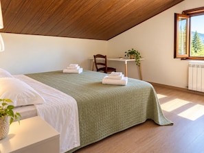 Een slaapkamer met een bed, een stoel, een tafel en een raam.