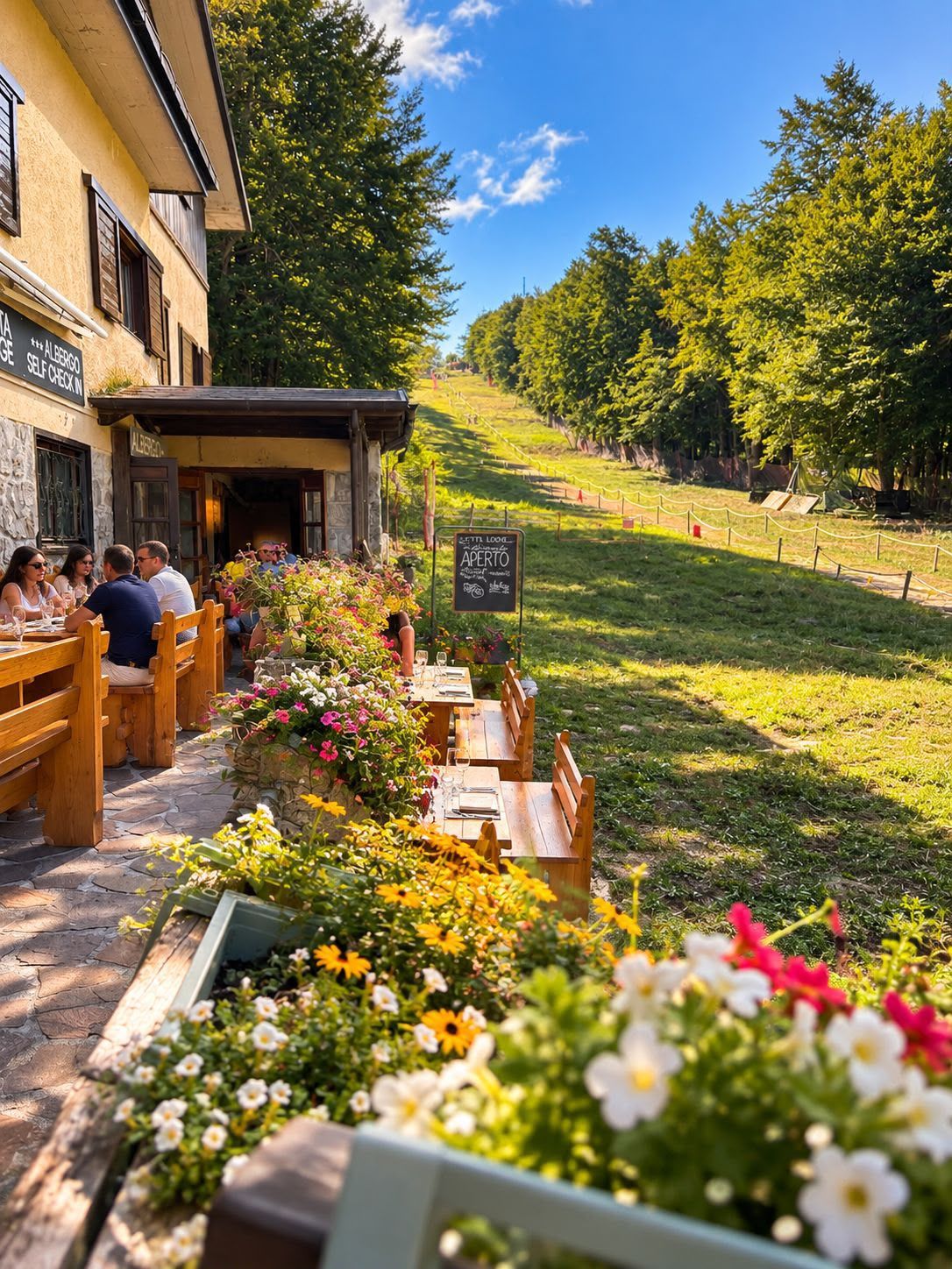An outdoor seating area with wooden benches and tables, surrounded by flower beds.