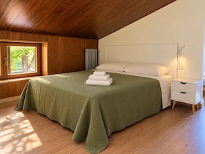 Een slaapkamer met een groot bed, een nachtkastje en een raam.