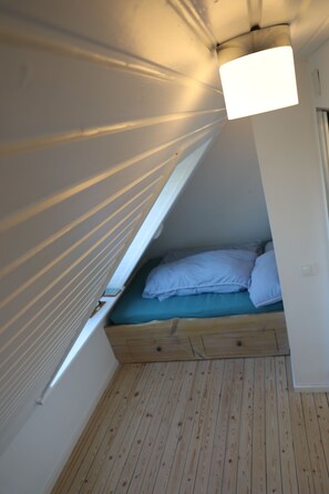 A small, enclosed sleeping area with a slanted ceiling and a single bed. - Vrbo Property (Neukirchen)
