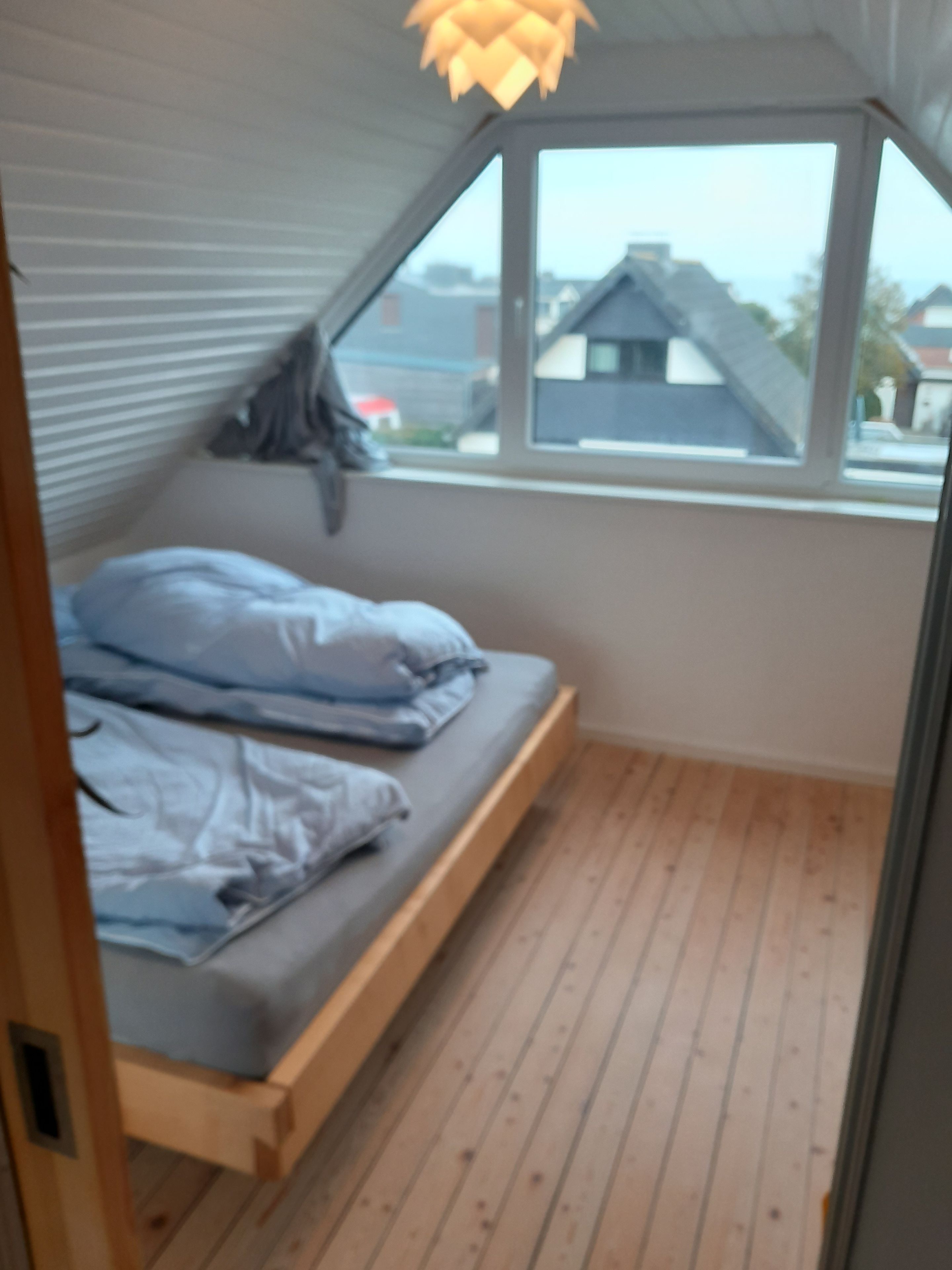 Ein Zimmer mit einem Bett, einem Fenster und Blick auf Gebäude.