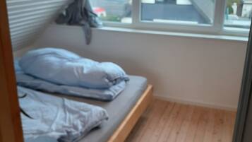 Ein Zimmer mit einem Bett, einem Fenster und Blick auf Gebäude.