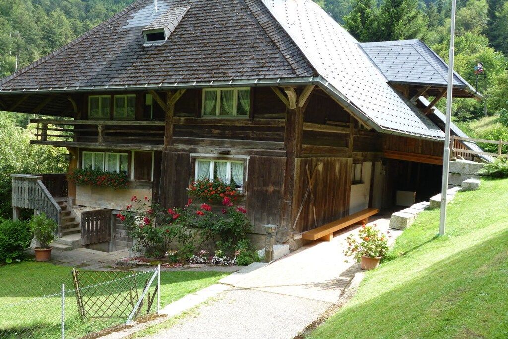 A wooden cabin with a sloped roof, a porch, and a small staircase leading to the entrance.