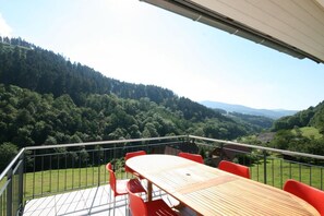 Una terraza con mesa y sillas, con vistas a un valle boscoso.