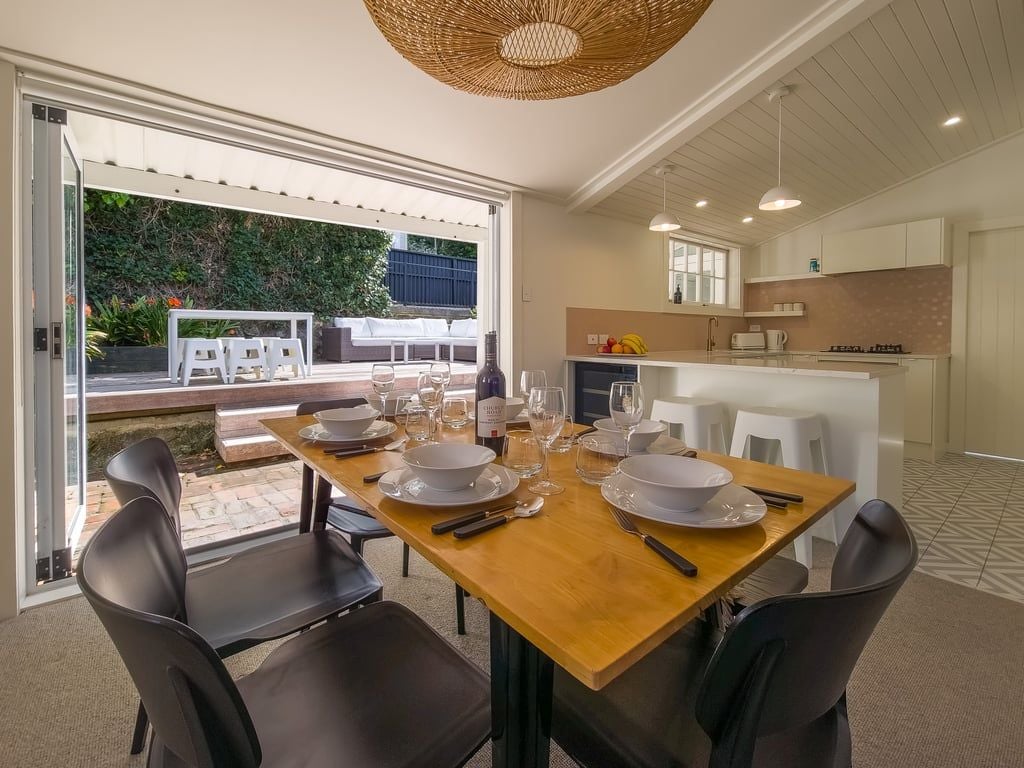 A dining area with a wooden table set for four, surrounded by modern chairs.