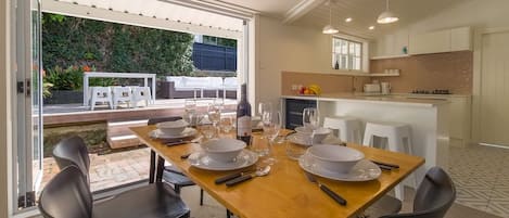 A dining area with a wooden table set for four, surrounded by modern chairs.