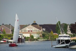 Ein Yachthafen mit vertäuten Segelbooten, ein Haus mit geneigtem Dach und ein klarer Himmel.