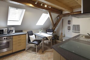 A compact kitchen with a dining area, a built-in oven, and a window above the sink. - Bär's holiday apartment (Eichstetten)