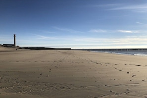 A sandy beach with footprints, a lighthouse, and a wooden pier extending into the water. - Holiday apartment with 2 bedrooms (Westkapelle)