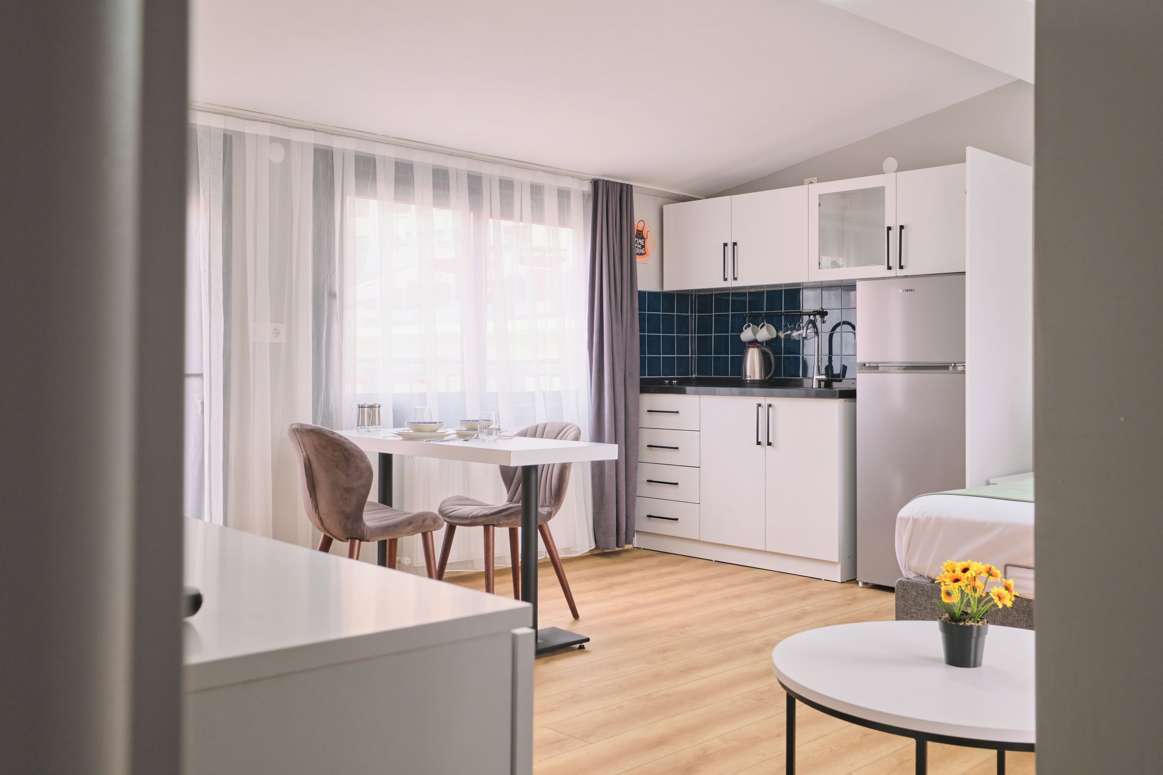 Una cucina moderna con mobili bianchi, un piano di lavoro nero e un bollitore in acciaio inossidabile.