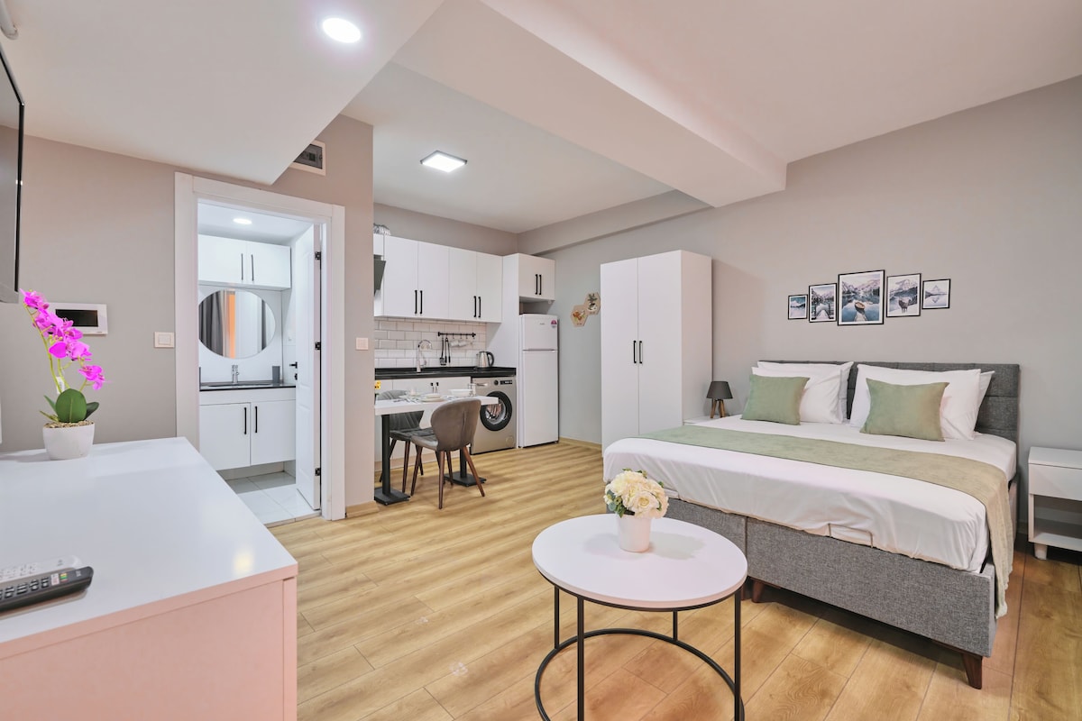 A modern bedroom with a bed, bedside table, and a small round table with flowers.