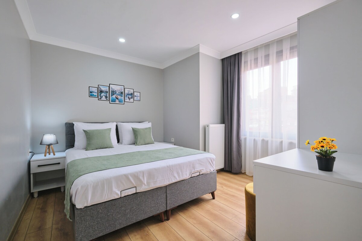 A modern bedroom with a bed, bedside table, lamp, and artwork on the wall.