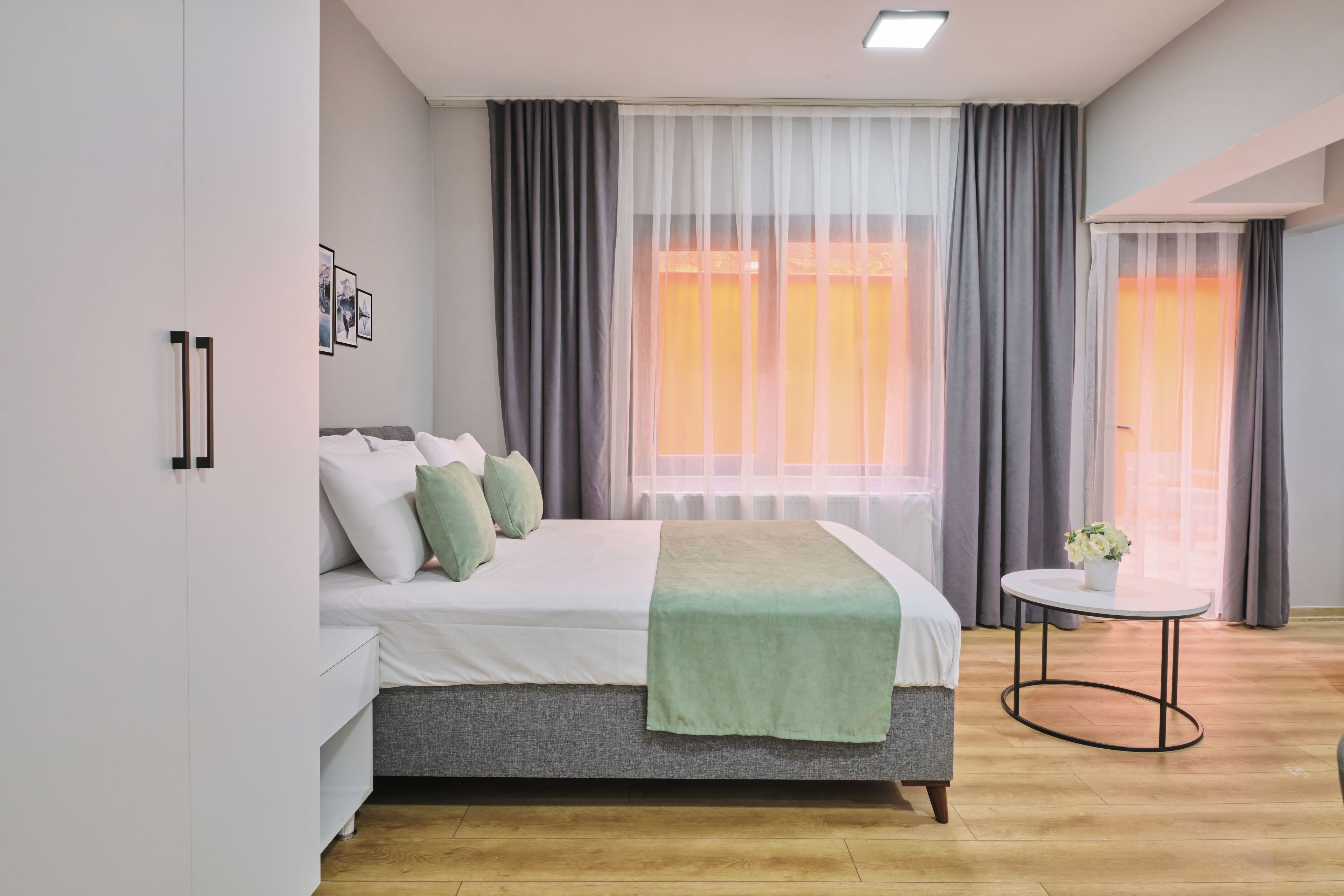 A modern bedroom with a bed, a bedside table, and a window with curtains.