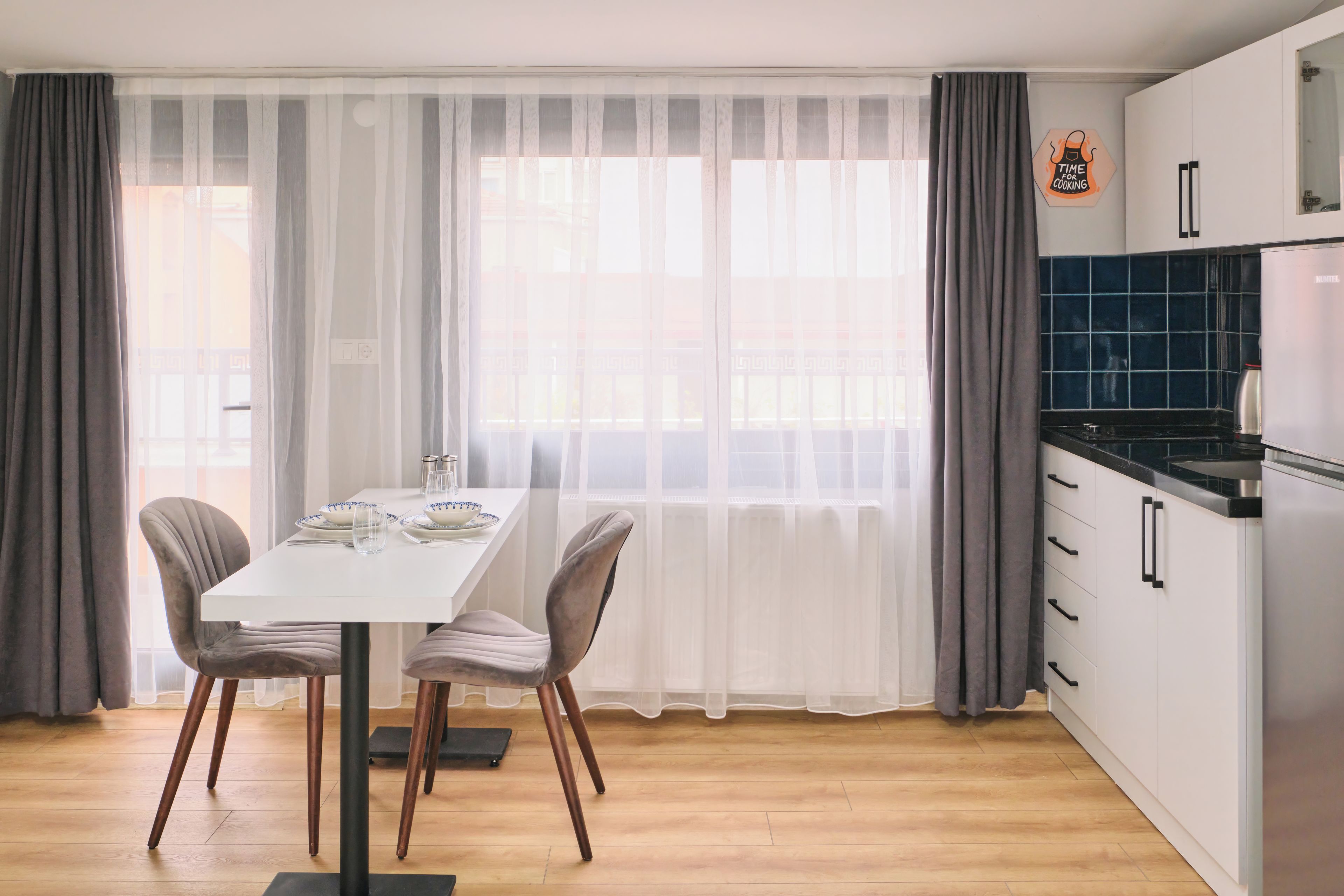 Une cuisine moderne avec des meubles blancs, un plan de travail noir et une cuisinière en acier inoxydable.