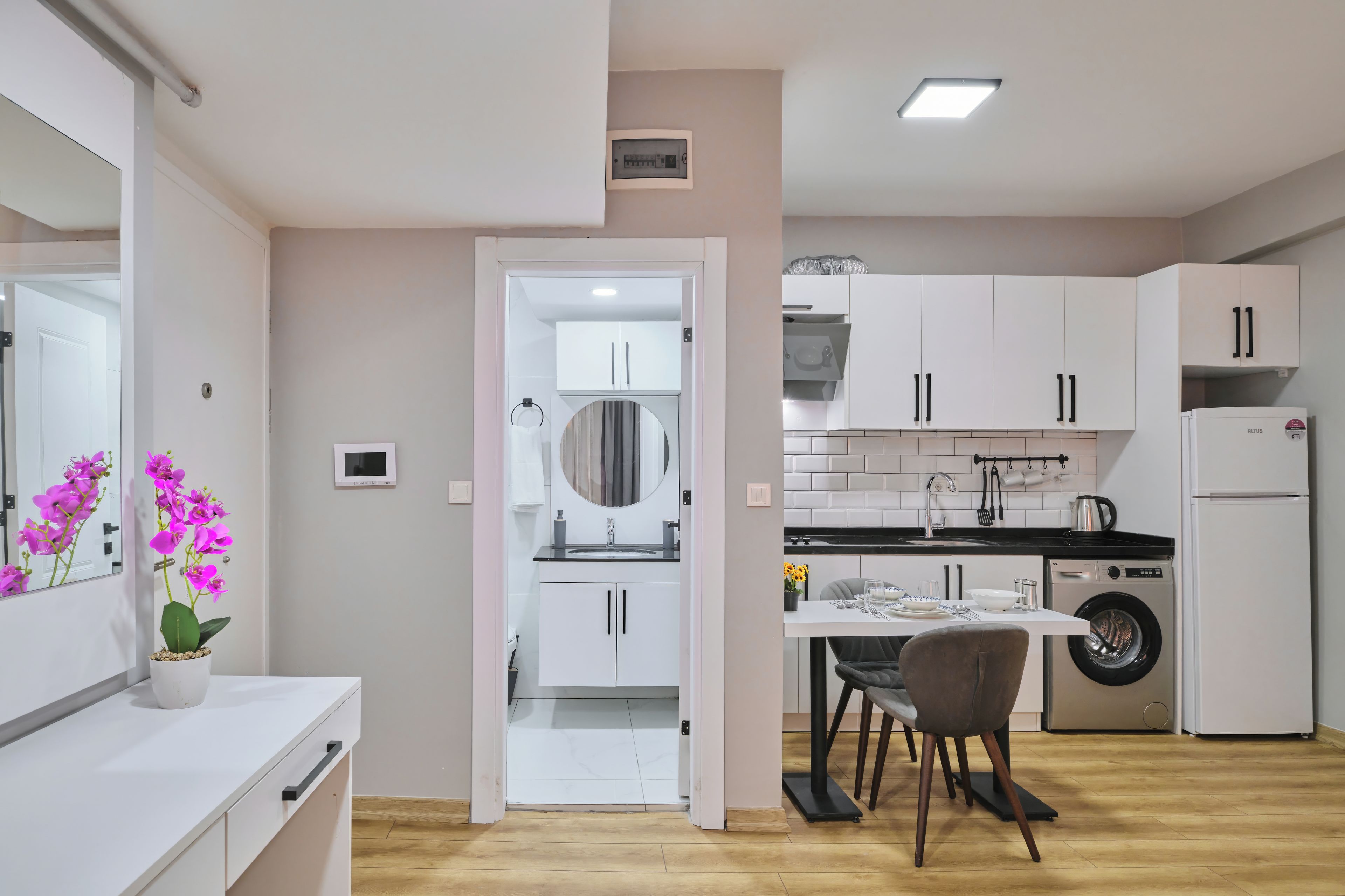 A modern kitchen with white cabinets, a built-in oven, and a washing machine.
