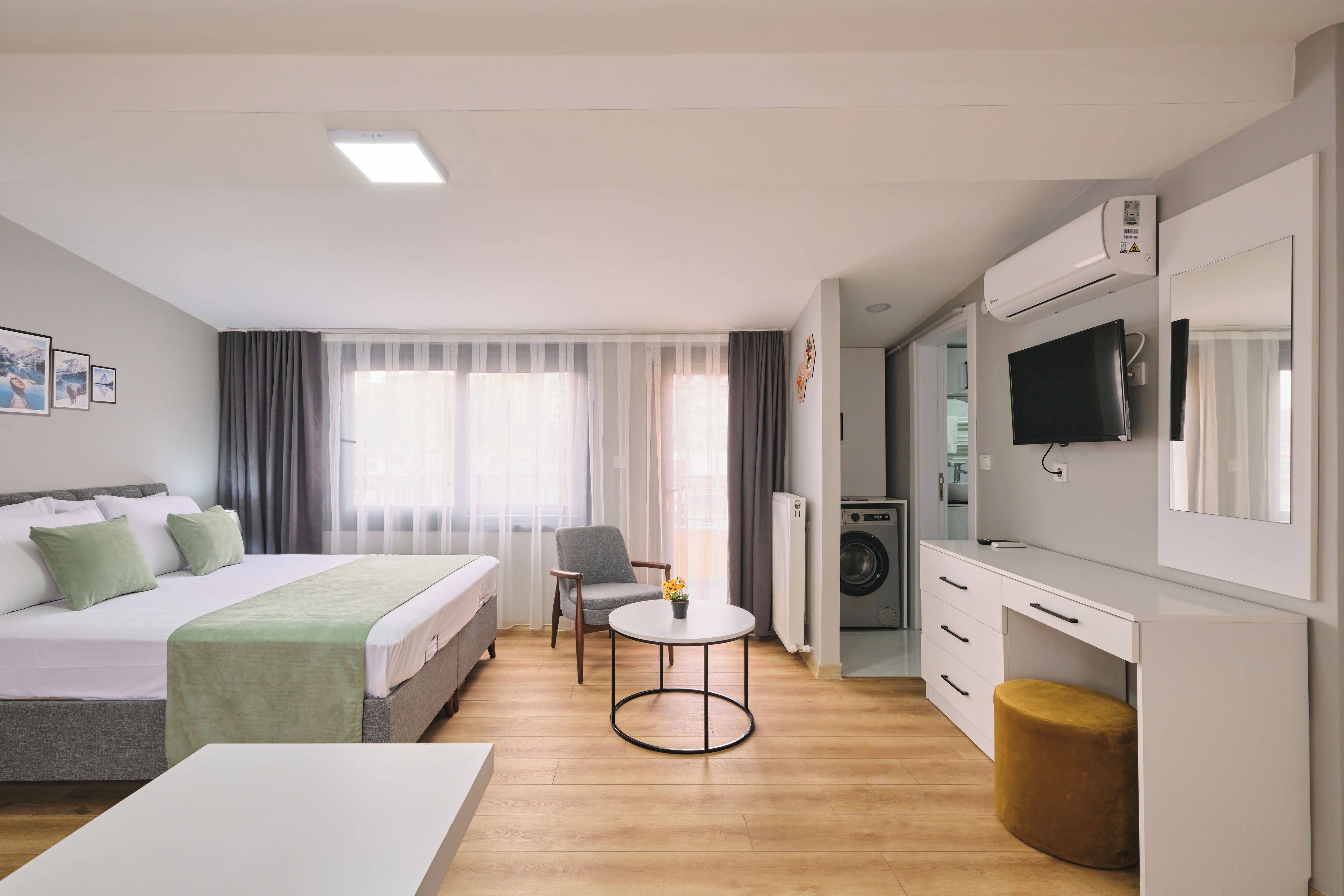 Una moderna camera d'hotel con un letto, un tavolino, una sedia, una lavatrice e una televisione.