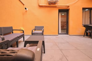 An outdoor seating area with wicker furniture, a tiled floor, and a door leading to a building. - ÜLKER APARTMENTS (Beyoğlu)