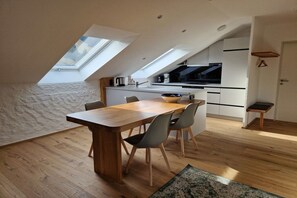 A modern kitchen with a skylight, wooden dining table, and chairs. - Holiday apartment with 2 bedrooms (Bad Hindelang)