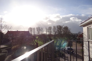 A residential area with a clear sky, a balcony with a metal railing, and a parked car. - Holiday apartment with 1 bedroom (oostkapelle)