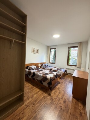 Quarto com uma cama, guarda-roupa de madeira e uma escrivaninha.