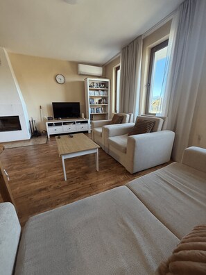 Una sala de estar con sofá, mesa de centro, estantería y televisor.