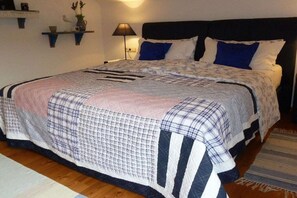 Une chambre à coucher avec un lit, des tables de chevet, une lampe et des étagères fixées au mur.