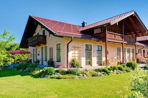 A two-story house with a red-tiled roof, a balcony, and a garden in front. - Holiday apartment with 2 bedrooms (Bischofswiesen)