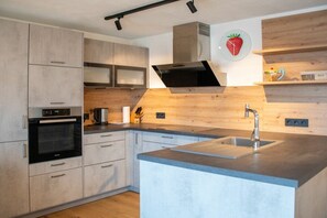 Eine moderne Küche mit Einbauofen, Spüle aus Edelstahl und Holzschränken.