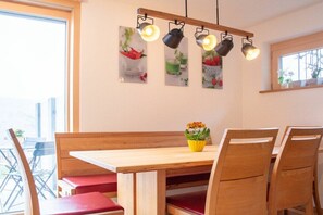 Ein Essbereich mit einem Holztisch und Bänken, einer gelben Blumenvase und Wandleuchten.