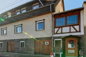 Ein mehrstöckiges Gebäude mit einer Steinfassade, Holzklappläden und einer Haustür mit einem Kranz.