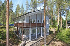 Ein zweistöckiges Holzhaus mit einem Balkon, umgeben von einem Wald.