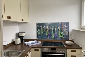 Een keuken met een inbouwoven, een koffiezetapparaat en een glazen vitrine.