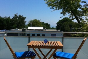 A rooftop terrace with a table and two chairs, a clear view of the sky, and a building in the background. - Holiday apartment with 1 bedroom (Konstanz)