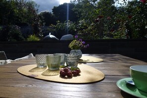 A wooden table with a placemat, three glass tumblers, a small vase with purple flowers, and a green cup on a saucer. - EifeLeben Bad Münstereifel (Bad Münstereifel)