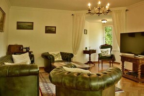 A living room with leather sofas, a television, and a sewing machine. - Holiday apartment with 3 bedrooms (Nassau)