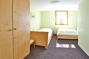 A room with two single beds, a wooden wardrobe, a small table, and a window with a view. - Holiday apartment with 2 bedrooms (St. Märgen)
