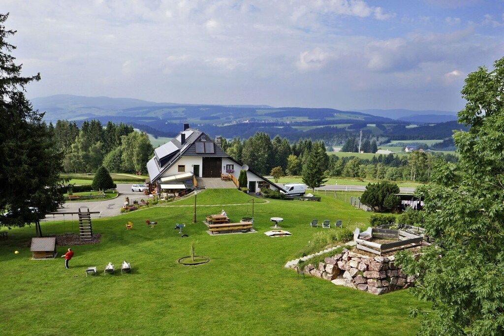 Ein Haus mit geneigtem Dach, einer Veranda und einem gepflegten Rasen.