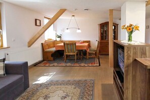 Ein Essbereich mit einem Holztisch, Stühlen, einem Holzschrank und einem Fernseher auf einem Holzboden.