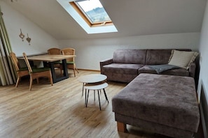 A loft-style room with a skylight, a sofa, a small table, and wicker chairs. - Holiday apartment with 1 bedroom (Bad Hindelang)