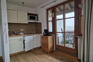 A compact kitchen with white cabinets, a microwave, a coffee maker, and a wooden cabinet. - Holiday apartment with 1 bedroom (Bad Hindelang)