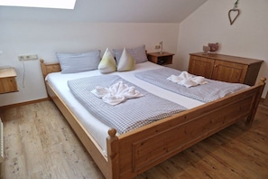 Ein Schlafzimmer mit einem hölzernen Bett, karierter Bettwäsche, einem Nachttisch und einer herzförmigen Dekoration an der Wand.