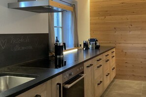Une cuisine moderne avec un plan de travail noir, un évier en acier inoxydable et des armoires en bois.