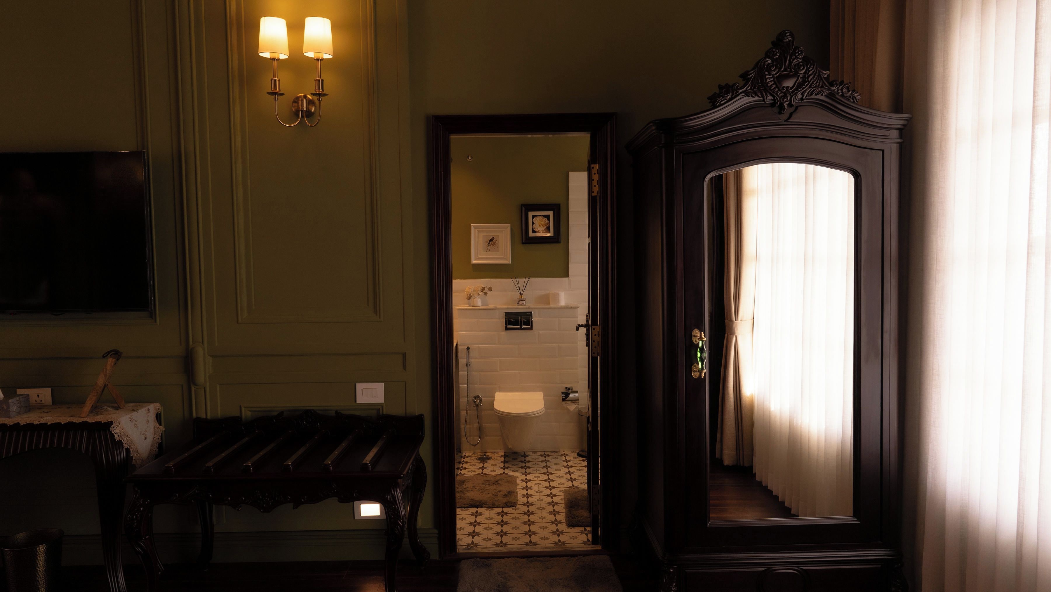 Un couloir avec un banc en bois, un miroir et une porte donnant sur une salle de bain.