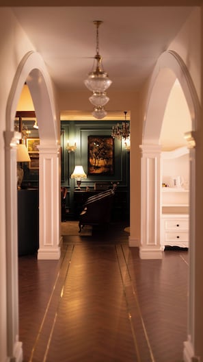 A hallway with a chandelier, a painting on the wall, and a staircase leading to another room. - KELSO (Ooty)