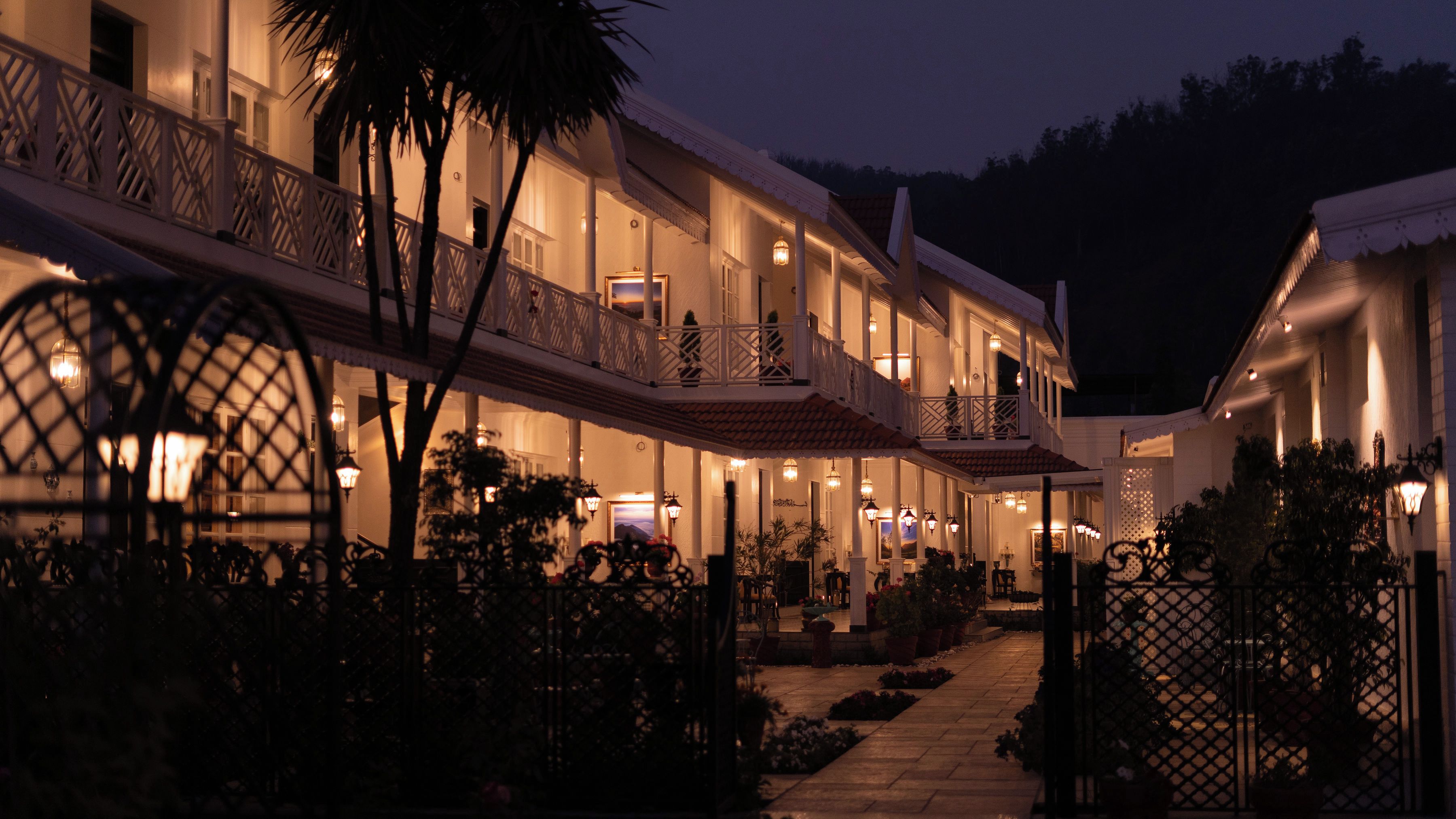 A multi-story hotel with balconies, outdoor seating, and a well-lit entrance.
